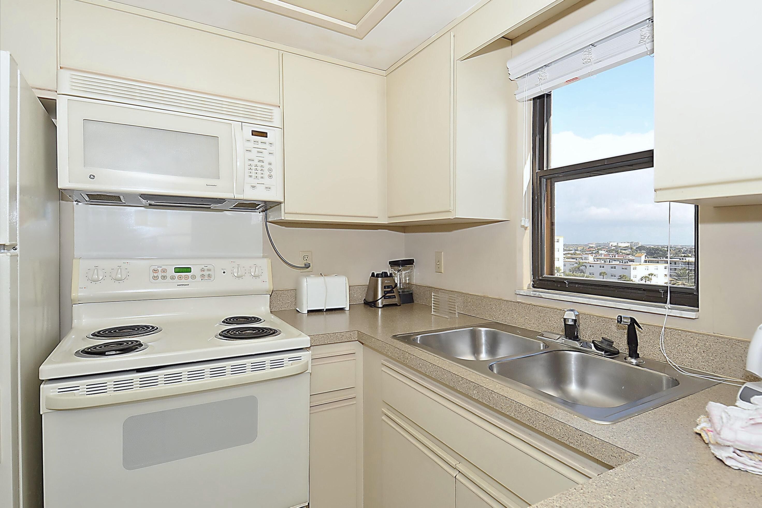 A compact kitchen with a stove, microwave, toaster, and two sinks.