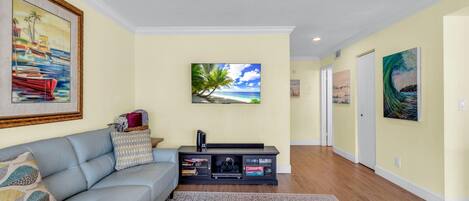 Una sala de estar con sofá, mesa de centro y mueble para televisión con dispositivos electrónicos.