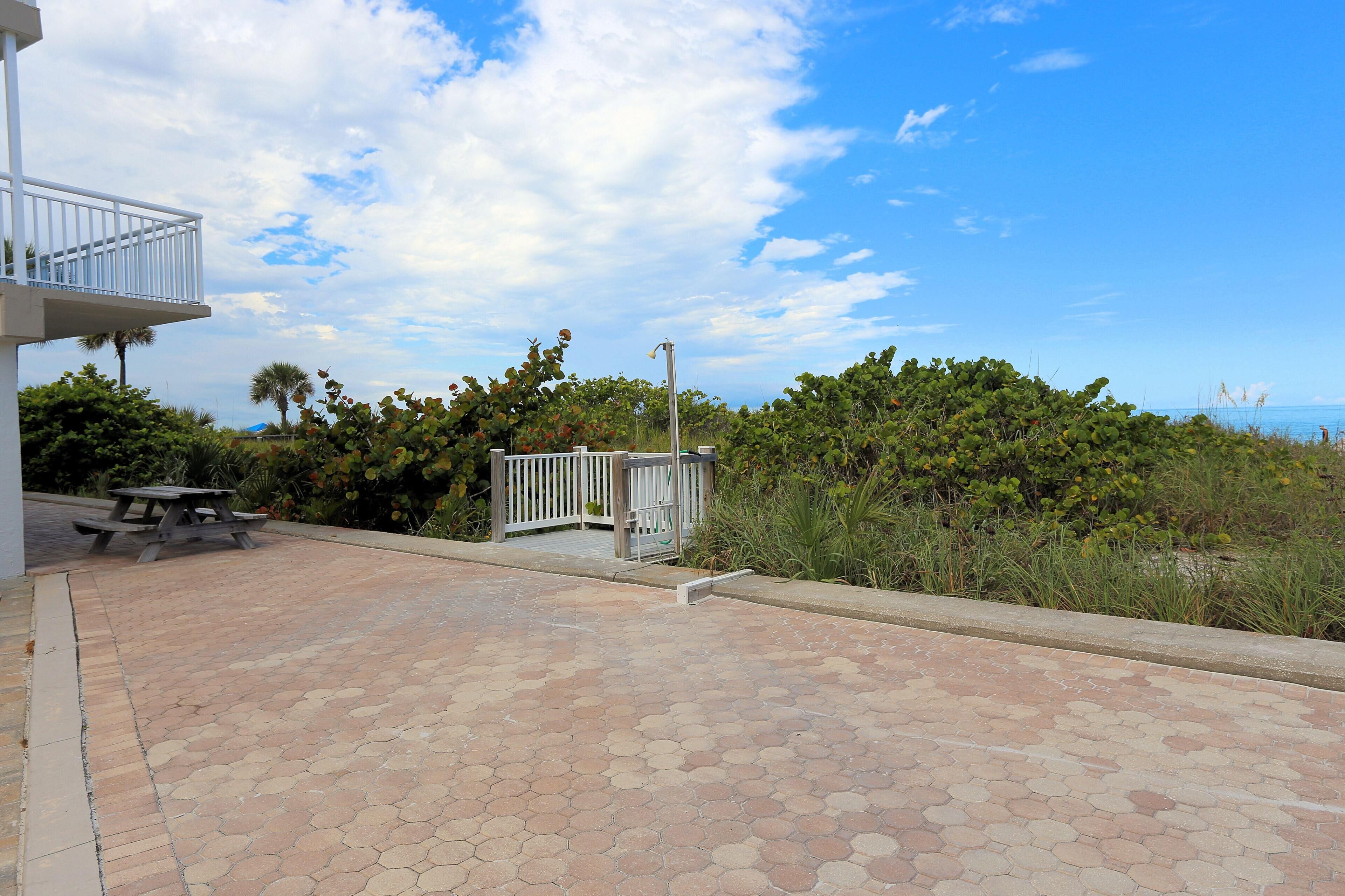 A paved patio area with a picnic table and a white fence.