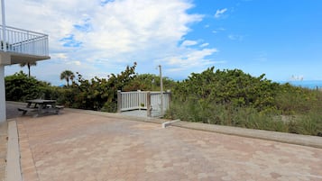 A paved patio area with a picnic table and a white fence.