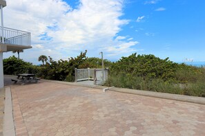 A paved patio area with a picnic table and a white fence. - Gulfside Villas 3 (Indian Rocks Beach)