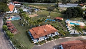 Luchtbeeld van een resort met een zwembad, een overdekt gedeelte met een rood dak en een omheind gazon met palmboom.