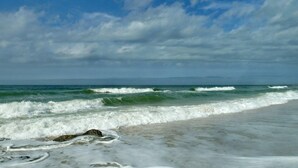 Una playa con olas y un cielo nublado.