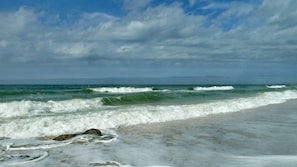 A beach with waves and a cloudy sky.