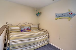 Un dormitorio con una cama, un letrero en la pared y un pequeño estante con adornos.