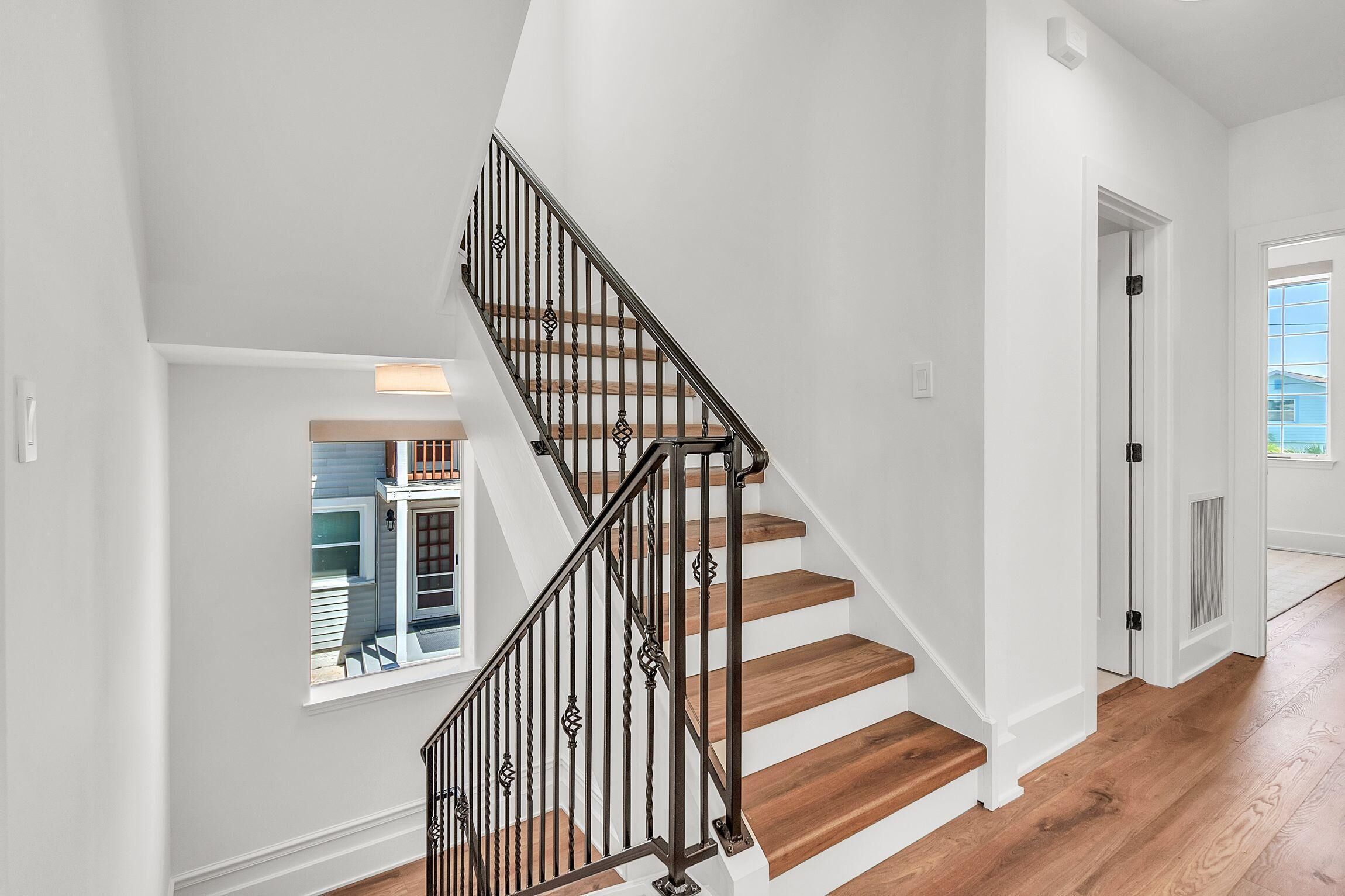 A staircase with wooden steps and black metal railings, leading to a door with a window.