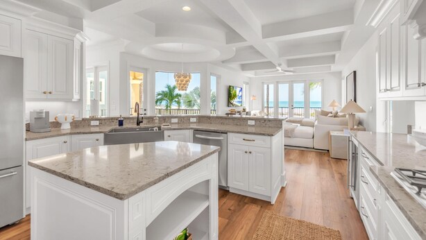 A spacious kitchen with white cabinetry, a large island, and a view of the beach.