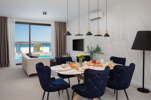 Un coin repas avec une table dressée pour quatre personnes, un canapé et une vue sur la mer.