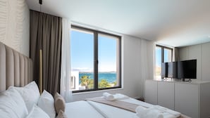 Habitación de hotel con una cama grande, televisión y vista al mar.
