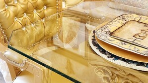 A luxurious room with a golden upholstered sofa, a glass coffee table with intricate designs, and a white ornate side table. - Exquisite, one of a kind place located in Lake Las Vegas Resort. Lovely decor  (Henderson)