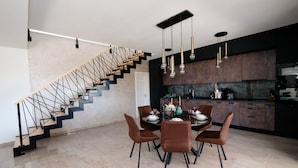 A modern kitchen with dark cabinets, a marble countertop, and a dining area with a round table and brown chairs. - Villa Emerilla with Pool (Pula)