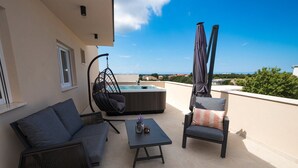 A rooftop terrace with a sofa, a chair, a table, a hanging chair, and a hot tub. - Villa Emerilla with Pool (Pula)