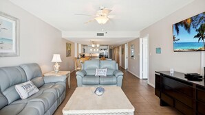 A living room with a light blue sofa, a white coffee table, and a ceiling fan. - Las Brisas 202 (Madeira Beach)