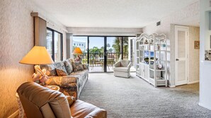 A spacious living area with a sofa, armchair, and a white shelving unit. - Land's End 1-307 Gulf View (Treasure Island)