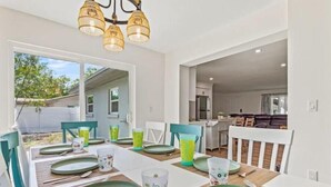 A dining area with a large table set for six, a kitchen in the background, and a view of the backyard. - Relaxing pool, Elegant and FUN vacation home! (Clearwater)