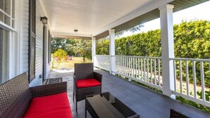 A covered porch with wicker furniture and a white railing.