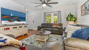 A living room with a sofa, a coffee table, a TV, and a ceiling fan.