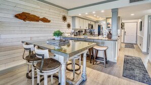 A modern kitchen with a central island, wooden wall paneling, and a large fish decoration. - Land's End 10-202 Beach Front - Premier (Treasure Island)