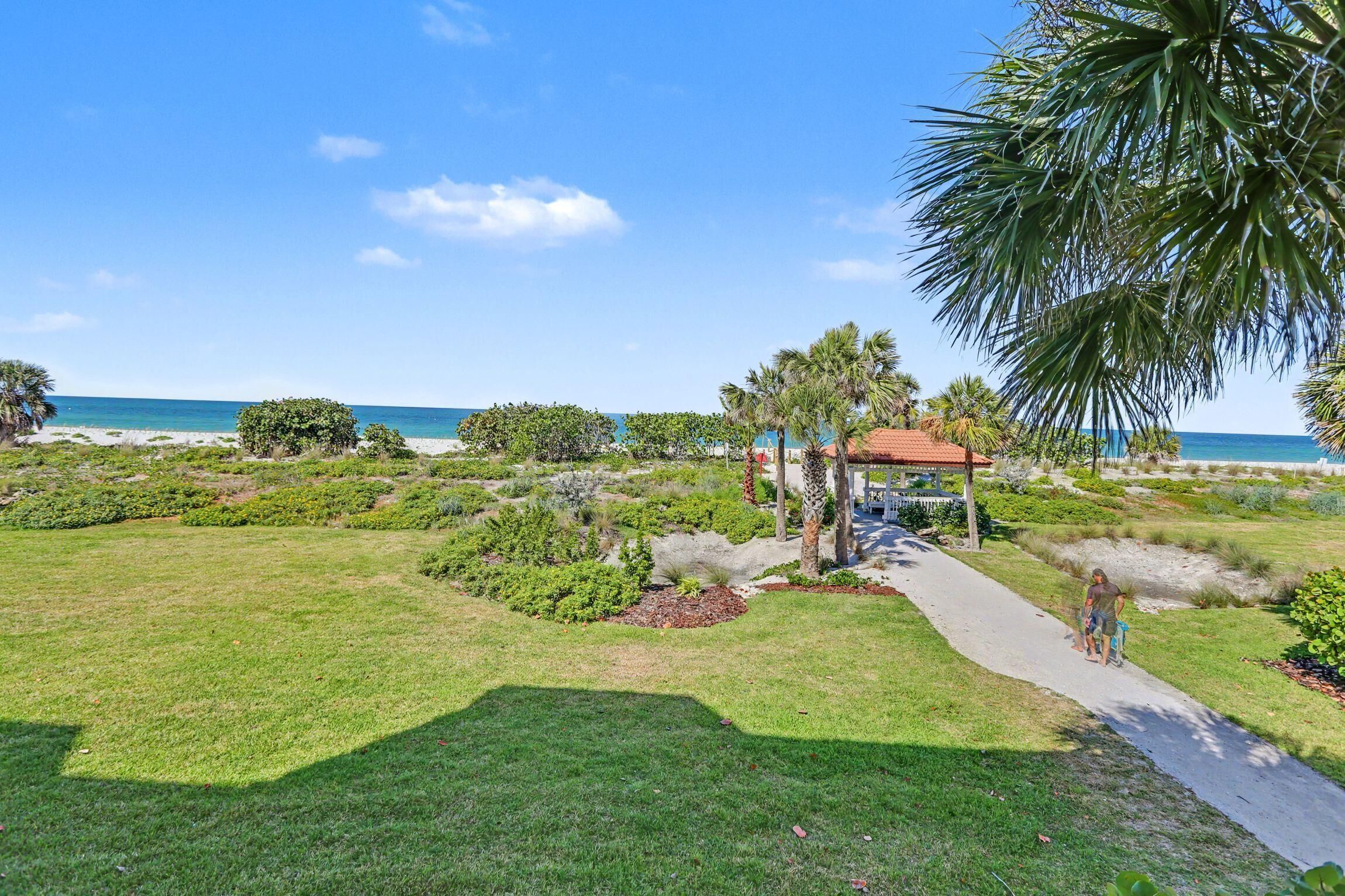 A pathway leading to a gazebo with a view of the beach.