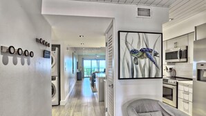 A modern kitchen with stainless steel appliances, a gray sofa, and a framed artwork on the wall.