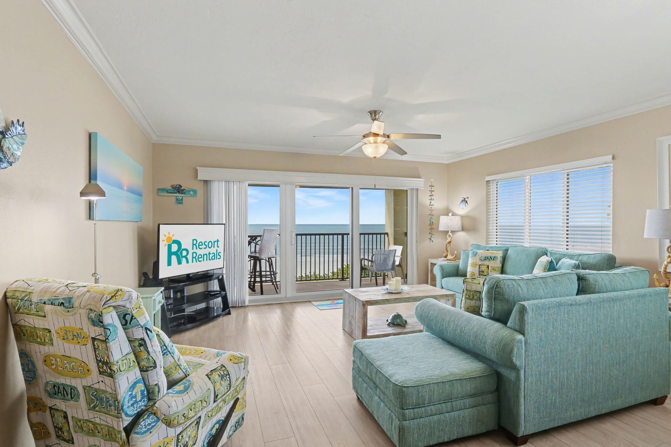 Ein Wohnzimmer mit einer Couch, einem Sessel und einem Couchtisch. Ein Fernseher und ein Schild mit der Aufschrift Resort Rentals sind ebenfalls vorhanden.