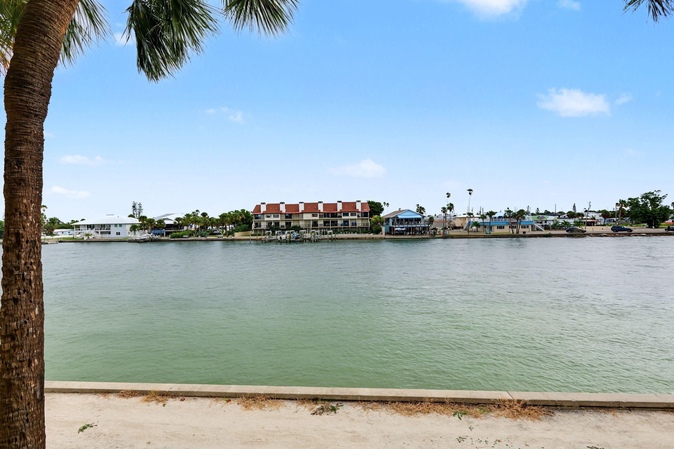 A waterfront property with a large building, docked boats, and a sandy beach.