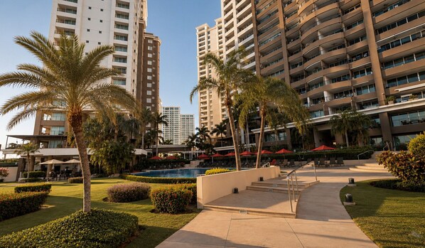 A hotel with multiple high-rise buildings, a swimming pool, and well-maintained gardens.