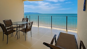 Un balcon avec vue sur la mer, une table ronde avec des chaises et une rambarde.