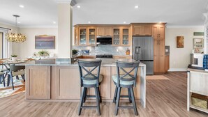 A modern kitchen with a central island, wooden cabinets, and a stainless steel refrigerator. - Land's End 3-301 Bay Front - Premier (Treasure Island)