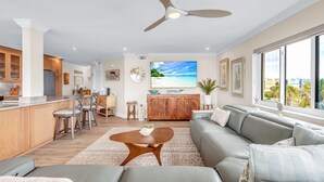 A modern living space with a kitchen, dining area, and a large window with a view. - Land's End 3-301 Bay Front - Premier (Treasure Island)