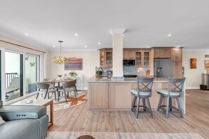 A modern kitchen with a central island, wooden cabinets, and a dining area with a table and chairs.