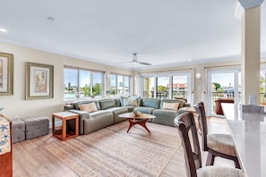 A spacious living room with a sectional sofa, a coffee table, and a dining area with a marble countertop.