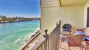 A balcony with wicker furniture, a view of a river, and a cityscape in the background. - Land's End 4-304 Bay Front - Premier (Treasure Island)