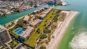 An aerial view of a coastal residential area with a marina, a tennis court, and a beach. - Land's End 4-304 Bay Front - Premier (Treasure Island)