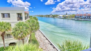 A waterfront hotel with a view of the water, palm trees, and a clear sky. - Land's End 4-401 Bay Front - Premier (Treasure Island)
