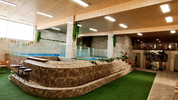 Zona de piscina con una barandilla de piedra, asientos y una baranda de cristal.
