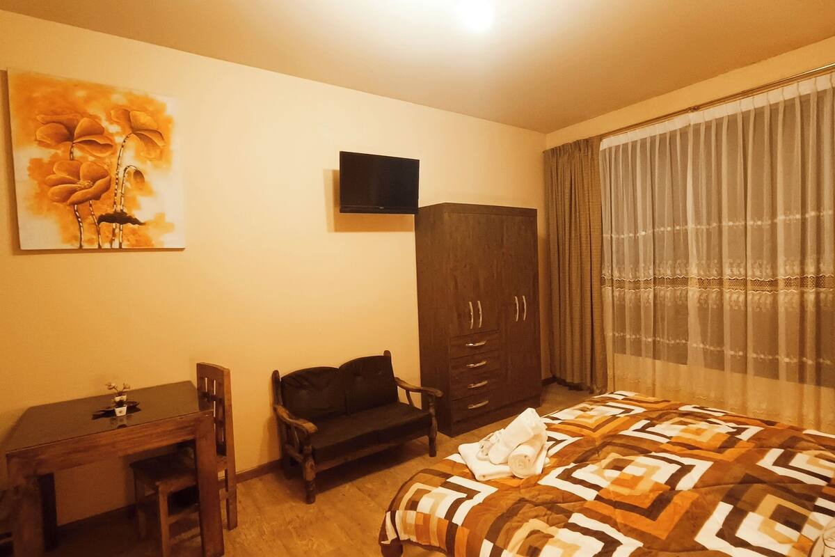 Une chambre d’hôtel avec un lit, un bureau, une armoire et un tableau au mur.