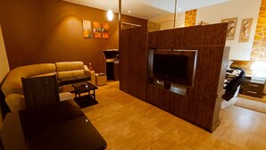 Una sala de estar moderna con un sofá, una mesa de centro, un televisor montado en una pared de madera y obras de arte en las paredes.