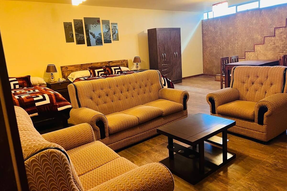 Un salon avec des canapés à motifs, une table basse et un coin repas comprenant des chaises et une table.