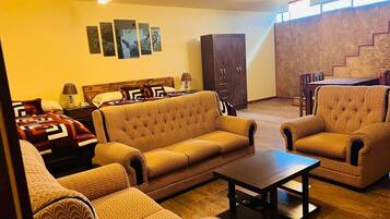 Una sala de estar con sofás estampados, una mesa de centro y un comedor con sillas y una mesa.
