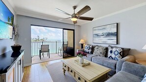 Un salon moderne avec un balcon, un ventilateur de plafond, un canapé, une table basse et un téléviseur.