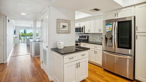 Une cuisine moderne avec des meubles blancs, des appareils en acier inoxydable et un plancher en bois.