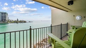 Ein Balkon mit Blick auf ein Gewässer, einer Wanduhr und einem Geländer.