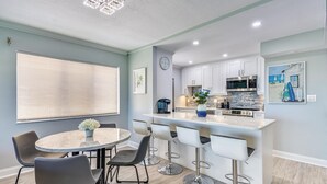 A modern kitchen with white cabinets, a stainless steel microwave, and a coffee maker. - Land's End 6-205 Beach Front - Premier (Treasure Island)