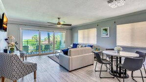 A spacious living area with a sofa, chairs, a dining table, and a ceiling fan. - Land's End 6-205 Beach Front - Premier (Treasure Island)