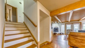 A staircase with wooden steps leading to a room with a fireplace, a sofa, and a view of the outdoors. - Scenic Alto Getaway w/ Mountain Views & Hot Tub! (Alto)