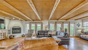 A spacious living room with a fireplace, leather sofas, and large windows offering views of the outdoors. - Scenic Alto Getaway w/ Mountain Views & Hot Tub! (Alto)
