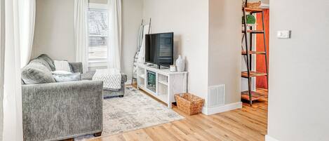 A living room with a grey sofa, a television, and a white entertainment unit.