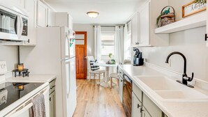 Een moderne keuken met witte kasten, een zwarte kraan en een houten vloer.