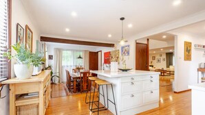 A modern kitchen with a central island, wooden flooring, and a dining area with a table and chairs.